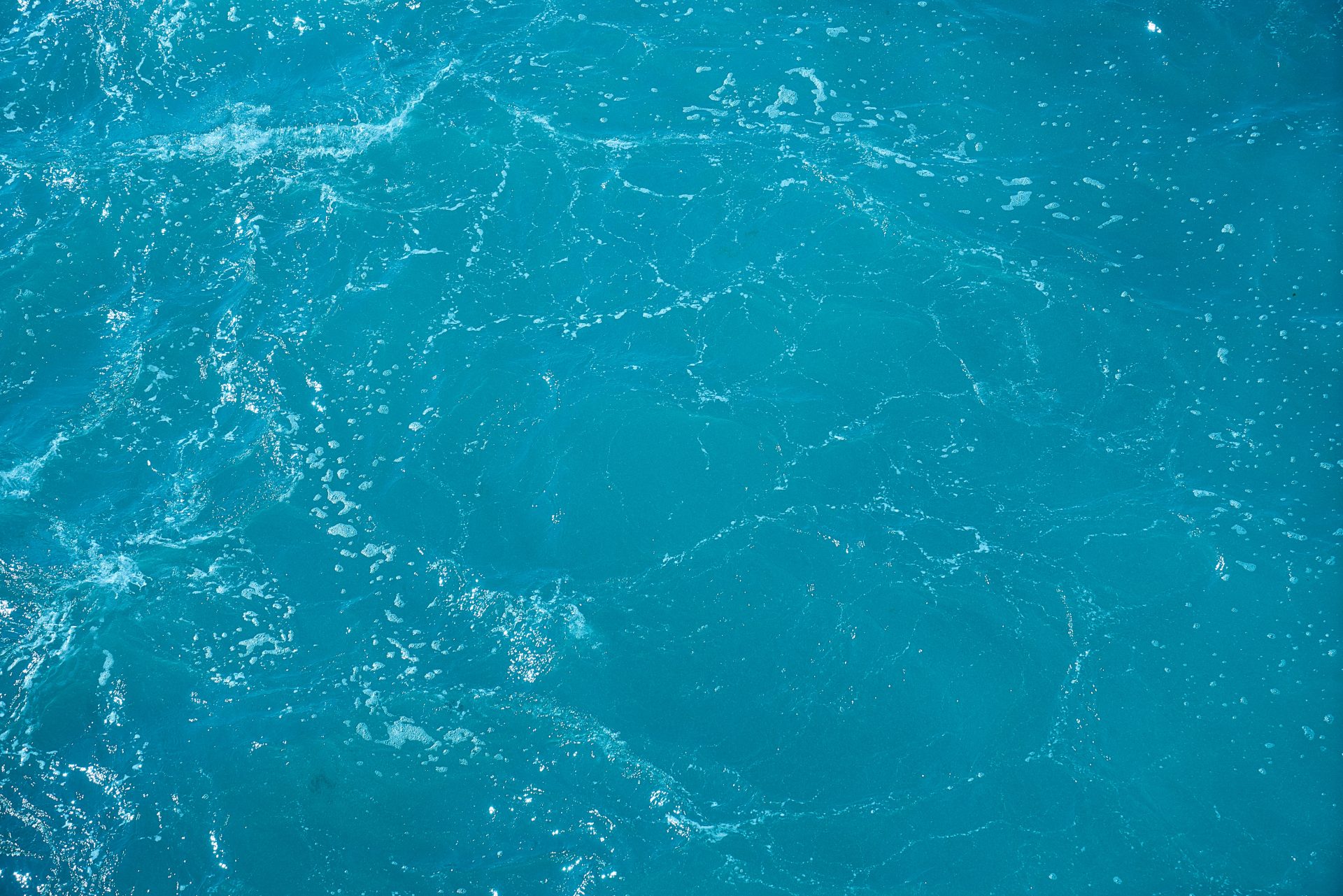 A detailed and vibrant view of turquoise ocean water with light reflections.